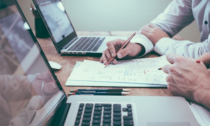 Deux personnes partageant une réflexion autour de 2 ordinateurs.