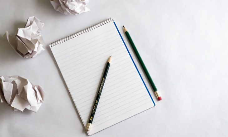 Photo d'un carnet de notes posé sur une table avec des crayons à papier.Feuille blanche, crayons et feuilles chiffonnées lors de l'écriture d'un article de blog.
