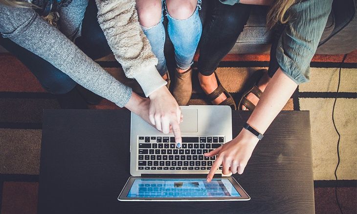 Photo de 3 personnes montrant du doigt un écran d'ordinateur 